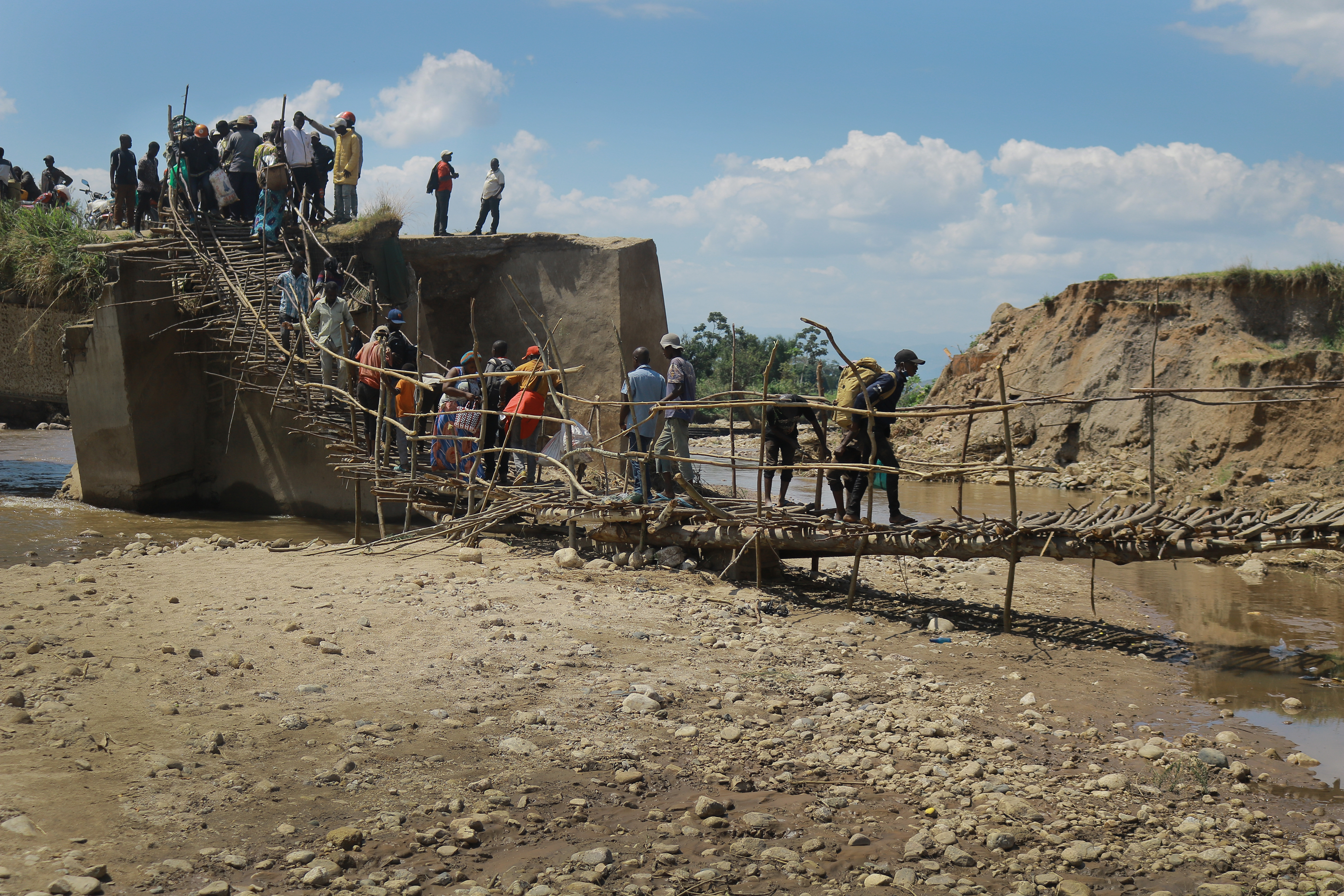 People walk over a wooden bridge built by United Methodist Men of Sange after the original bridge was washed away by mid-April flooding in Uvira, Congo. Photo by Philippe Kituka Lolonga, UM News.