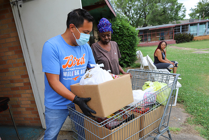 A volunteer from Tulsa Indian United Methodist Church loads up food boxes in a shopping cart so participants can take them home to a nearby apartment complex. Tulsa Indian United Methodist Church operates a food bank on the last Friday of the month. Photo by Ginny Underwood, UM News.
