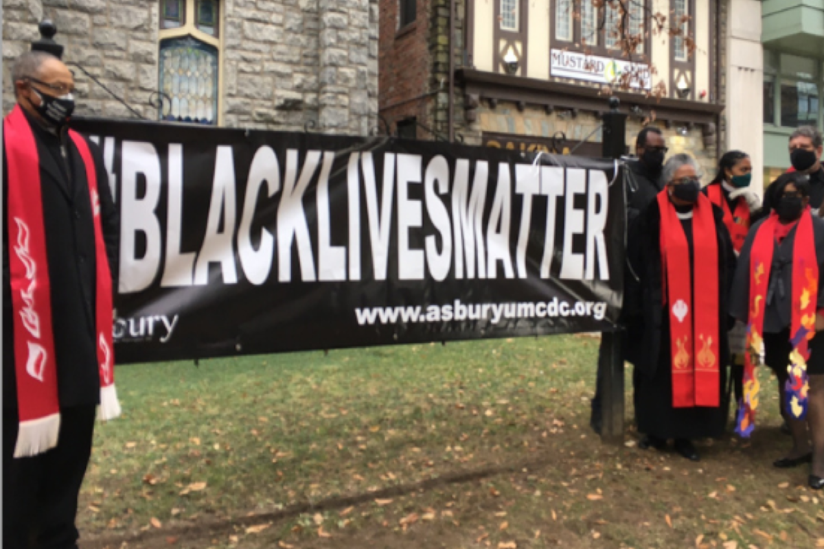 Faith leaders gather in front of Asbury UMC in Washington D.C., to hang a new Black Lives Matter banner after the previous one was torn down and burned by demonstrators on December 12, 2020. Photo by Erik Alsgaard.