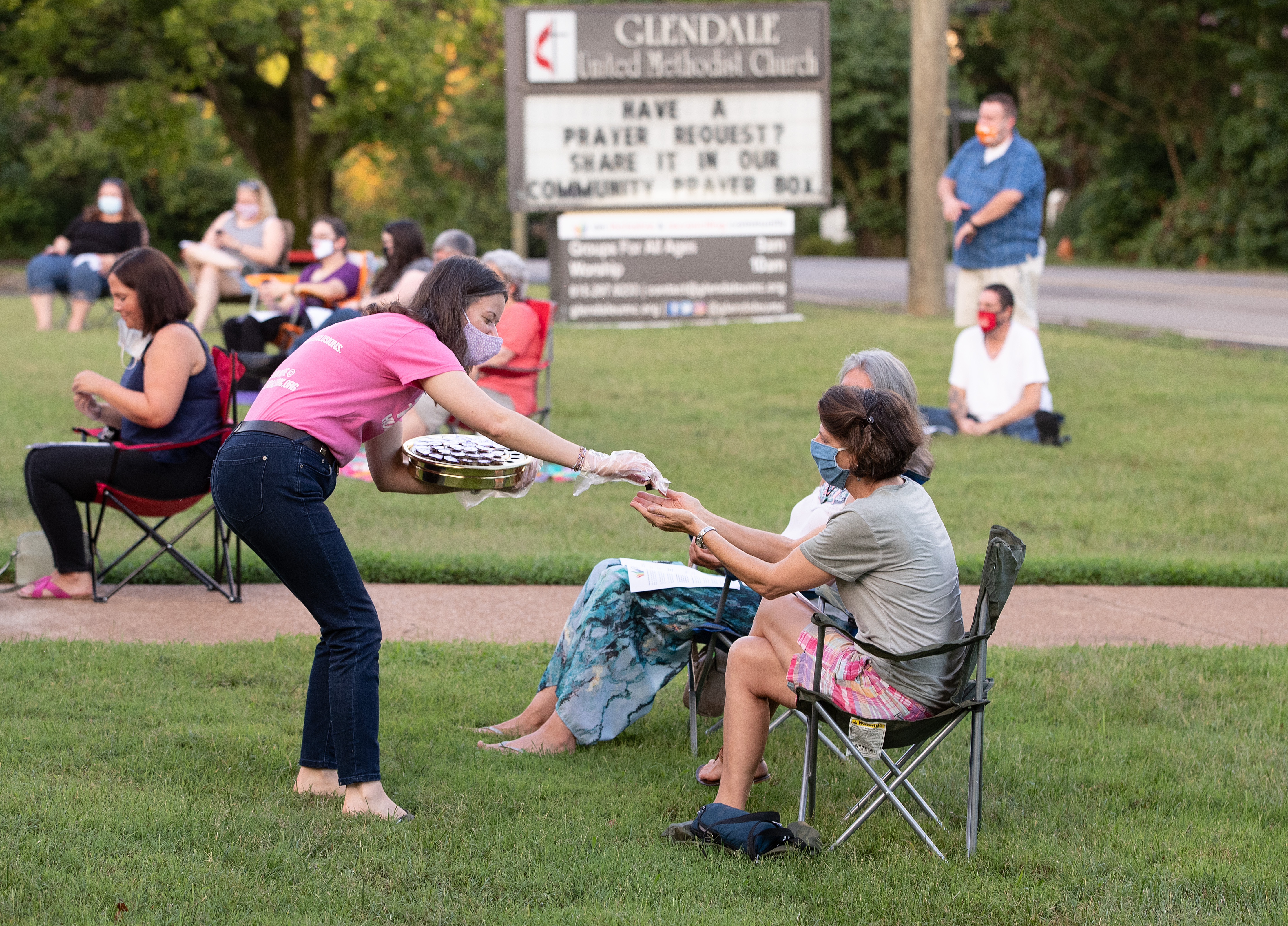 Laura Kreiselmaier serves Holy Communion during an outdoor worship service at Glendale United Methodist Church in Nashville, Tenn., July 26, 2020. UM News.