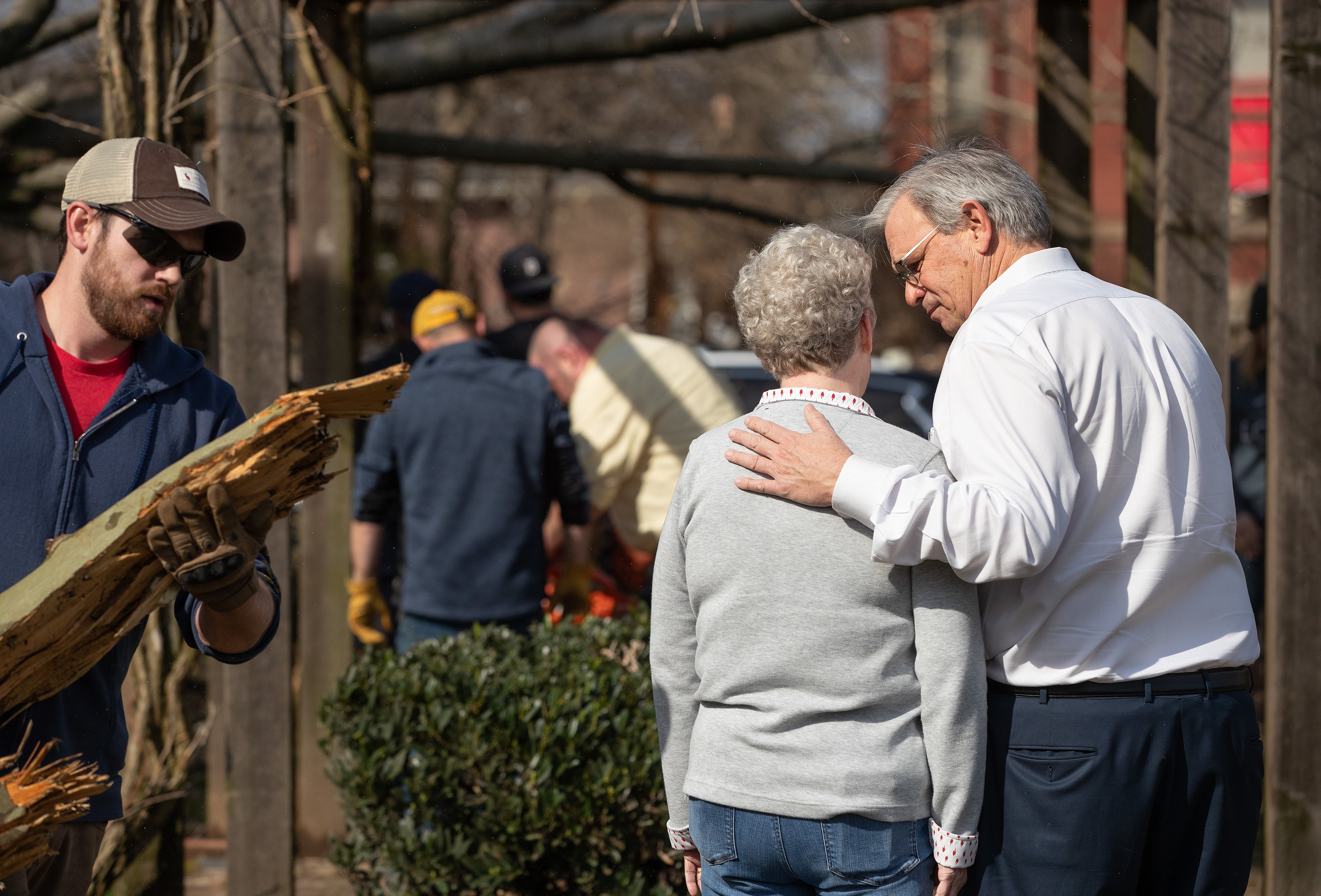 Bishop William McAlilly (right) comforts the Rev. Judi Hoffman in the park outside East End United Methodist Church in Nashville, Tenn., while volunteers clean up debris from a tornado that heavily damaged the church's sanctuary and offices. Photo by Mike DuBose, UM News.