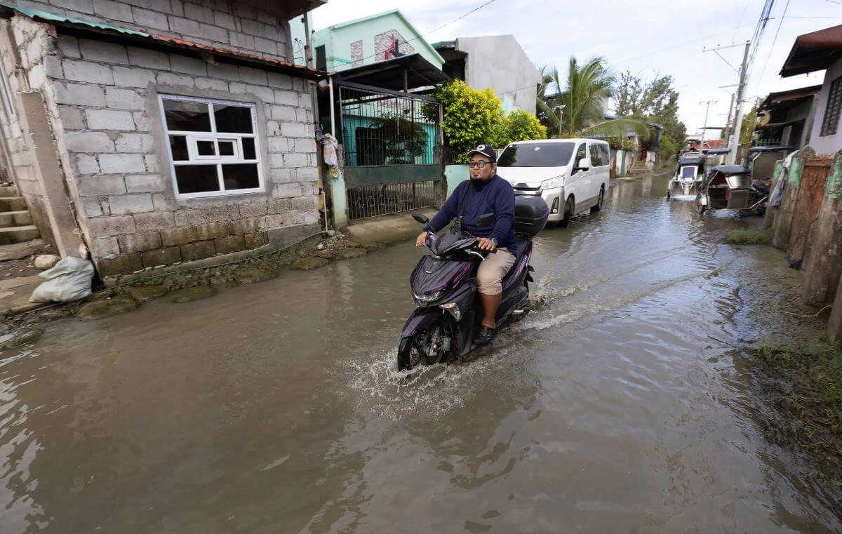 The Rev. Ishmael James Bolado rides his motorbike along the flooded road in front of Meysulao United Methodist Church in Calumpit, Philippines. Bolado and church members are continuing to support families forced from their homes some three months after Typhoon Carina struck the area. Because of the flooding, “most of the people can’t work,” he said. “No work, no pay.” (Photo: Photo: Mike DuBose, UM News)