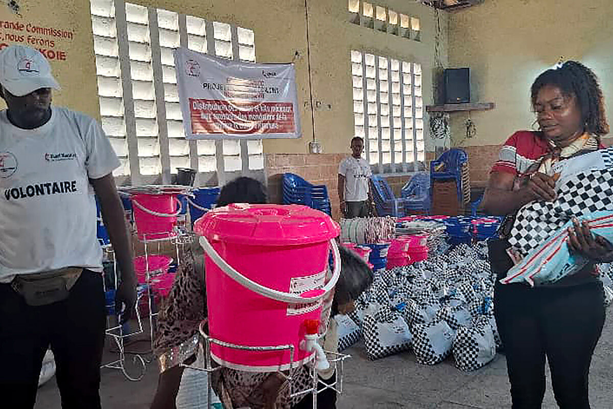 Joël Paradis, un volontaire du Bureau de Gestion des Catastrophes de l’UMCOR dans la Région Épiscopale du Congo Central, débout lors de l’opération de distribution à côté d’une bénéficiaire de l’aide des méthodistes unis. Des volontaires, parfois eux-mêmes touchés, ont bravé des routes impraticables pour acheminer l’aide, utilisant pirogues artisanales et portage manuel pour atteindre les zones isolées. Photo du Révérend Pasteur Fiston Okito, UM News.