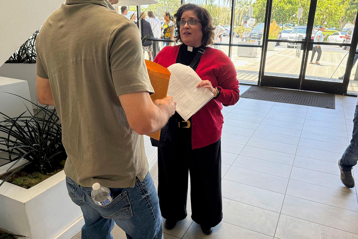El jueves 31 de julio de 2025 la Revda. Oona Casanova Vázquez, pastora principal de la Iglesia del Nazareno de South Bay en Torrance, habla con un hombre a quien acompañará a una audiencia en el Tribunal de Inmigración de Santa Ana, California. Foto cortesía de Deepa Bharath, AP.